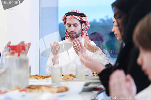 Image of traditional muslim family praying before iftar dinner