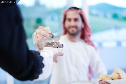 Image of Muslim family having Iftar dinner eating dates to break feast