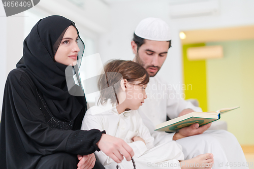 Image of muslim family reading Quran and praying at home