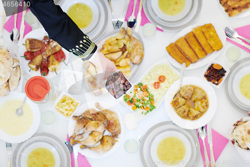 Image of Muslim family having Iftar dinner eating dates to break feast to