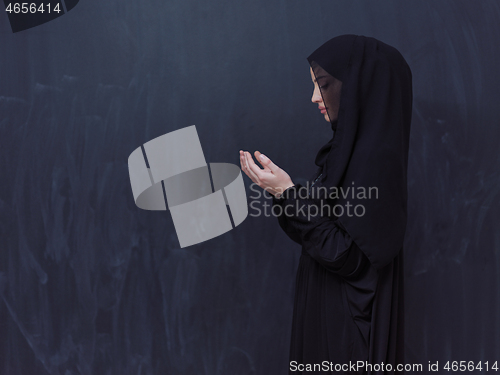 Image of muslim woman making traditional prayer to God in front of black 