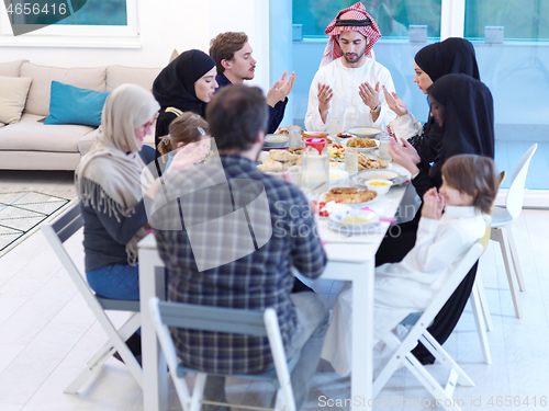 Image of traditional muslim family praying before iftar dinner