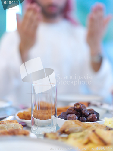 Image of arabian man making traditional prayer to God before iftar dinner