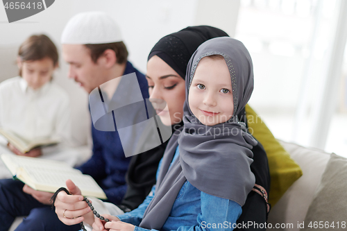 Image of muslim family reading Quran and praying at home