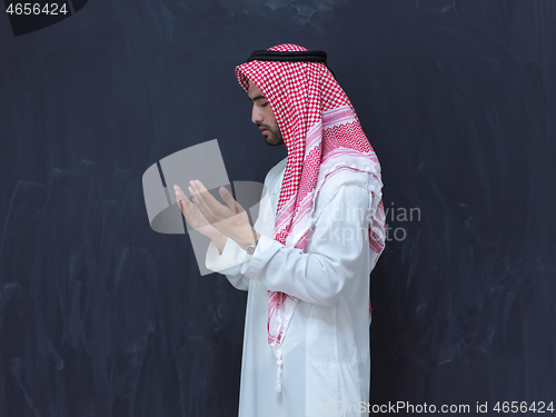 Image of arabian man making traditional prayer to God, keeps hands in pra