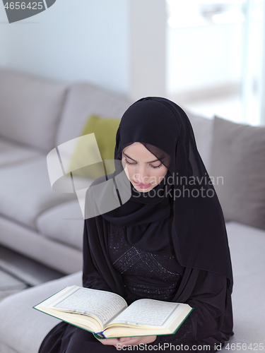 Image of young muslim woman reading Quran at home