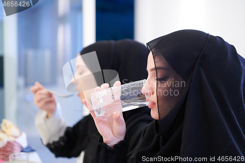 Image of Muslim family having Iftar dinner drinking water to break feast