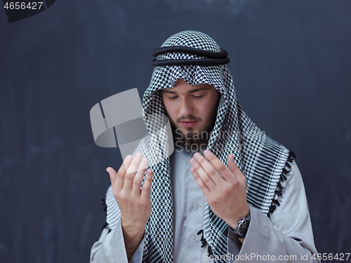 Image of arabian man making traditional prayer to God, keeps hands in pra