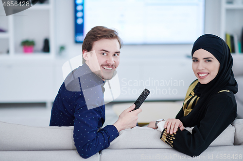 Image of young muslim couple watching TV together