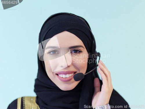 Image of portrait of muslim woman with headset on cyan background