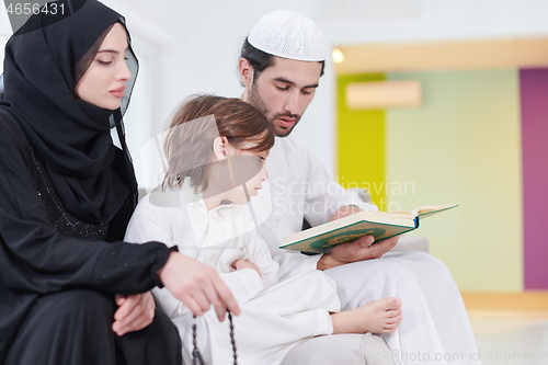 Image of muslim family reading Quran and praying at home