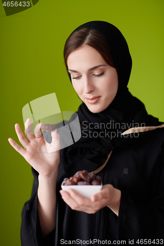 Image of Woman in Abaya Holding a Date Fruit and glass of water