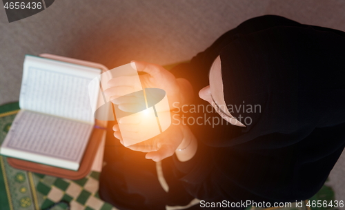 Image of Middle eastern woman praying and reading the holy Quran