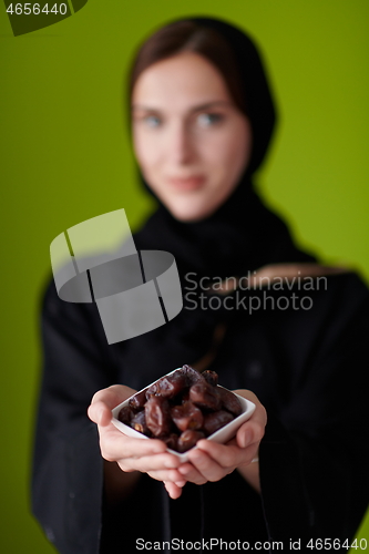 Image of Woman in Abaya Holding a Date Fruit and glass of water