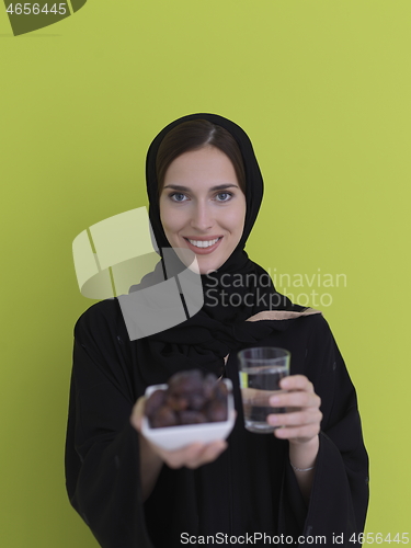 Image of Woman in Abaya Holding a Date Fruit and glass of water