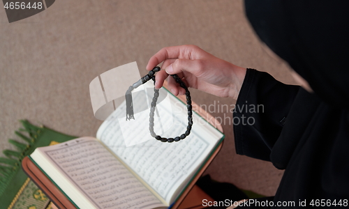 Image of Middle eastern woman praying and reading the holy Quran