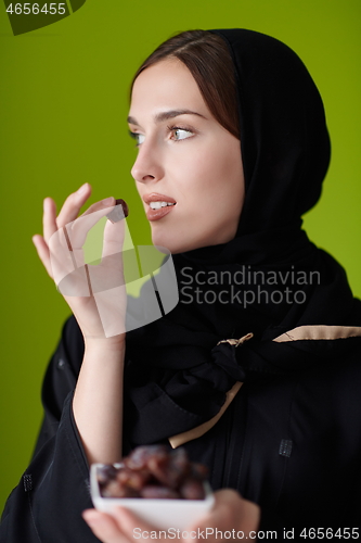 Image of Woman in Abaya Holding a Date Fruit and glass of water