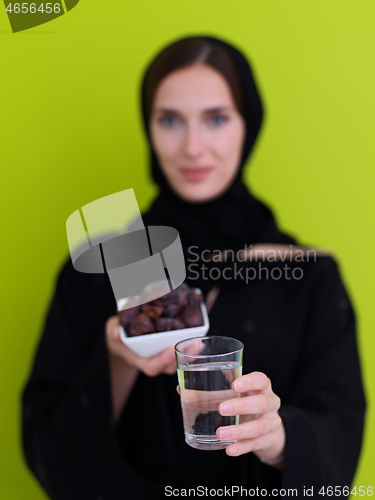 Image of Woman in Abaya Holding a Date Fruit and glass of water