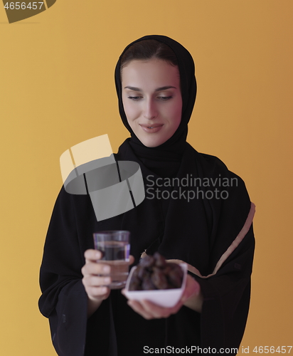 Image of Woman in Abaya Holding a Date Fruit and glass of water