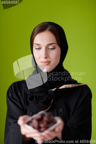 Image of Woman in Abaya Holding a Date Fruit and glass of water