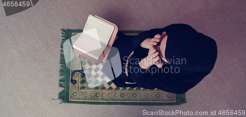 Image of Middle eastern woman praying and reading the holy Quran