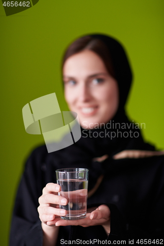 Image of Woman in Abaya Holding a Date Fruit and glass of water