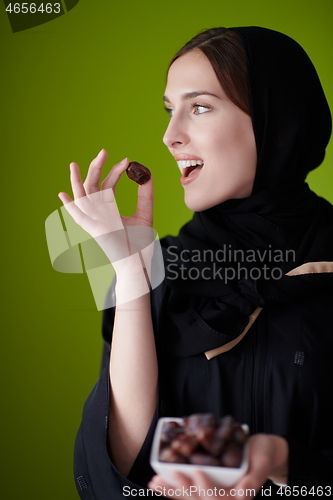 Image of Woman in Abaya Holding a Date Fruit and glass of water