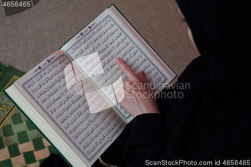 Image of Middle eastern woman praying and reading the holy Quran