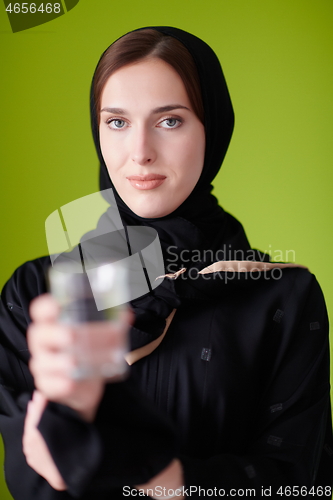 Image of Woman in Abaya Holding a Date Fruit and glass of water