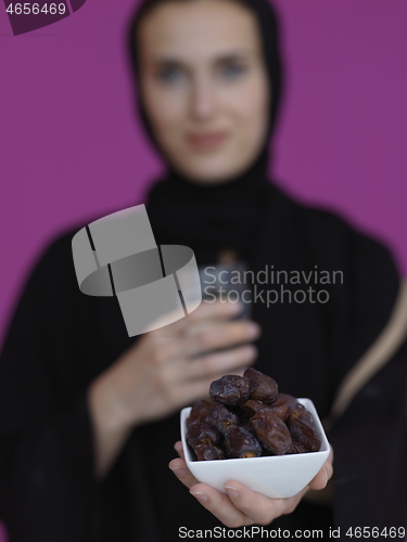 Image of Woman in Abaya Holding a Date Fruit and glass of water