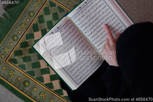 Image of Middle eastern woman praying and reading the holy Quran