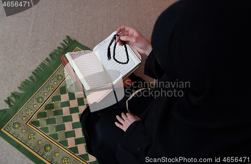 Image of Middle eastern woman praying and reading the holy Quran