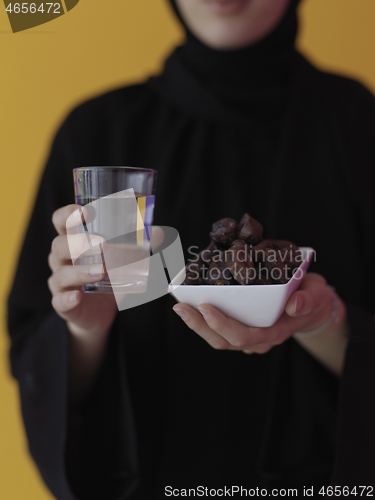 Image of Woman in Abaya Holding a Date Fruit and glass of water