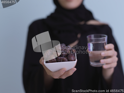 Image of Woman in Abaya Holding a Date Fruit and glass of water