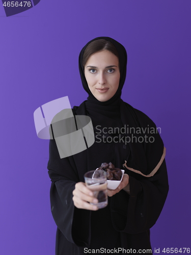 Image of Woman in Abaya Holding a Date Fruit and glass of water