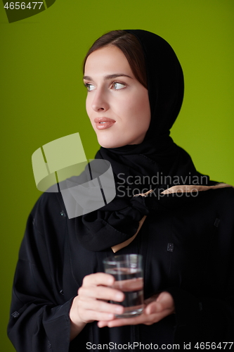 Image of Woman in Abaya Holding a Date Fruit and glass of water