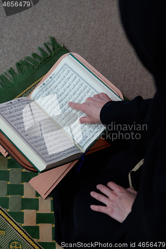 Image of Middle eastern woman praying and reading the holy Quran