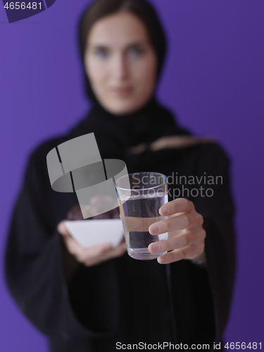 Image of Woman in Abaya Holding a Date Fruit and glass of water