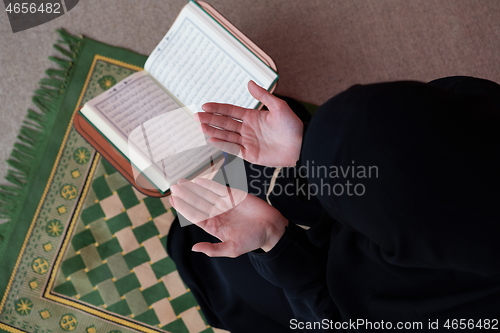 Image of Middle eastern woman praying and reading the holy Quran