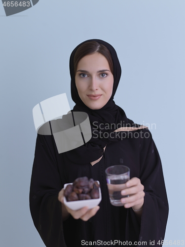 Image of Woman in Abaya Holding a Date Fruit and glass of water