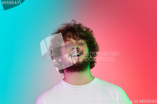 Image of Caucasian young man\'s portrait on gradient studio background in neon