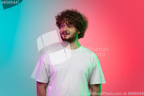 Image of Caucasian young man\'s portrait on gradient studio background in neon