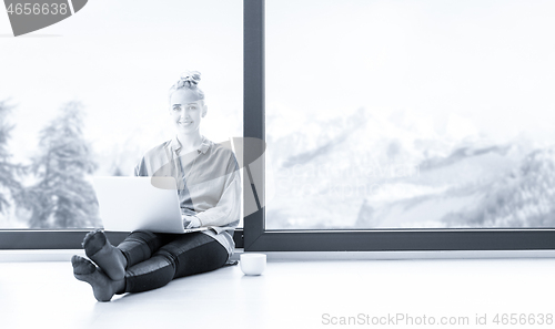 Image of woman drinking coffee and using laptop at home