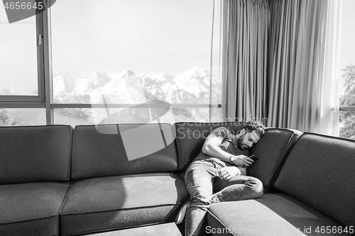 Image of young casual man using a mobile phone at home