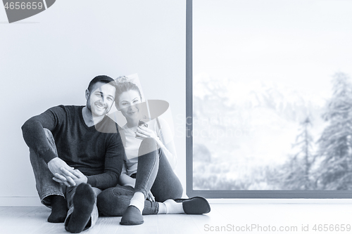 Image of young couple sitting on the floor near window at home