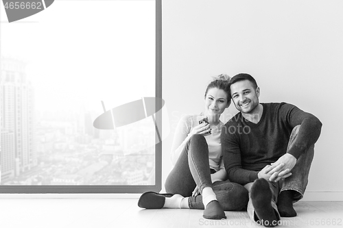 Image of young couple sitting on the floor near window at home