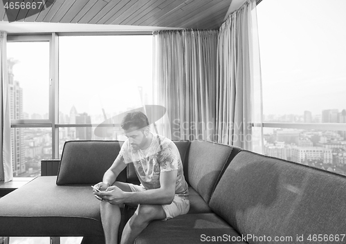 Image of young casual man using a mobile phone at home