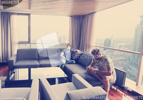 Image of two young men using a mobile phones  at home