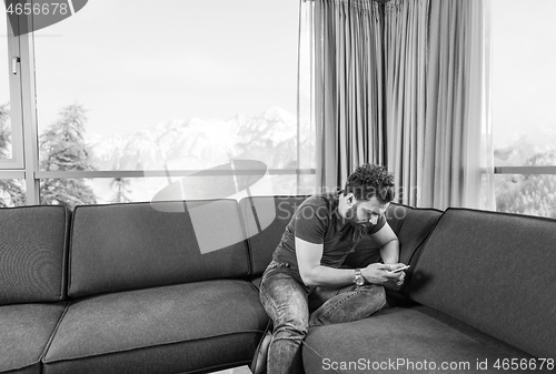 Image of young casual man using a mobile phone at home
