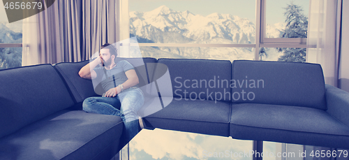 Image of young casual man using a mobile phone at home